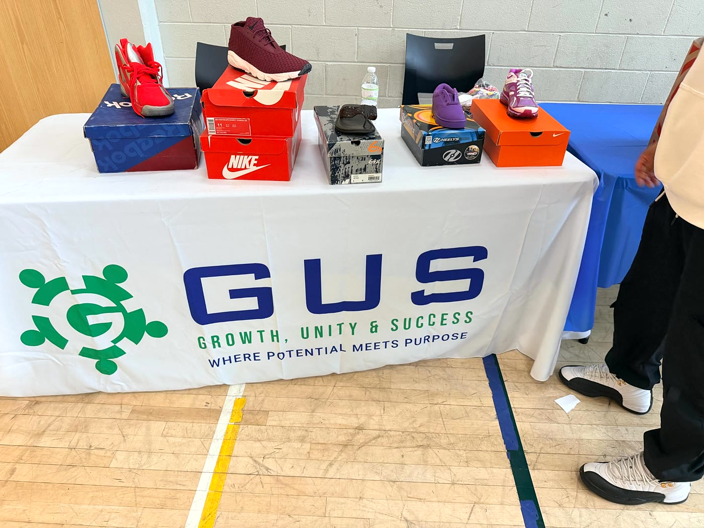 A table with a GUS banner holding sample sneakers on their boxes.